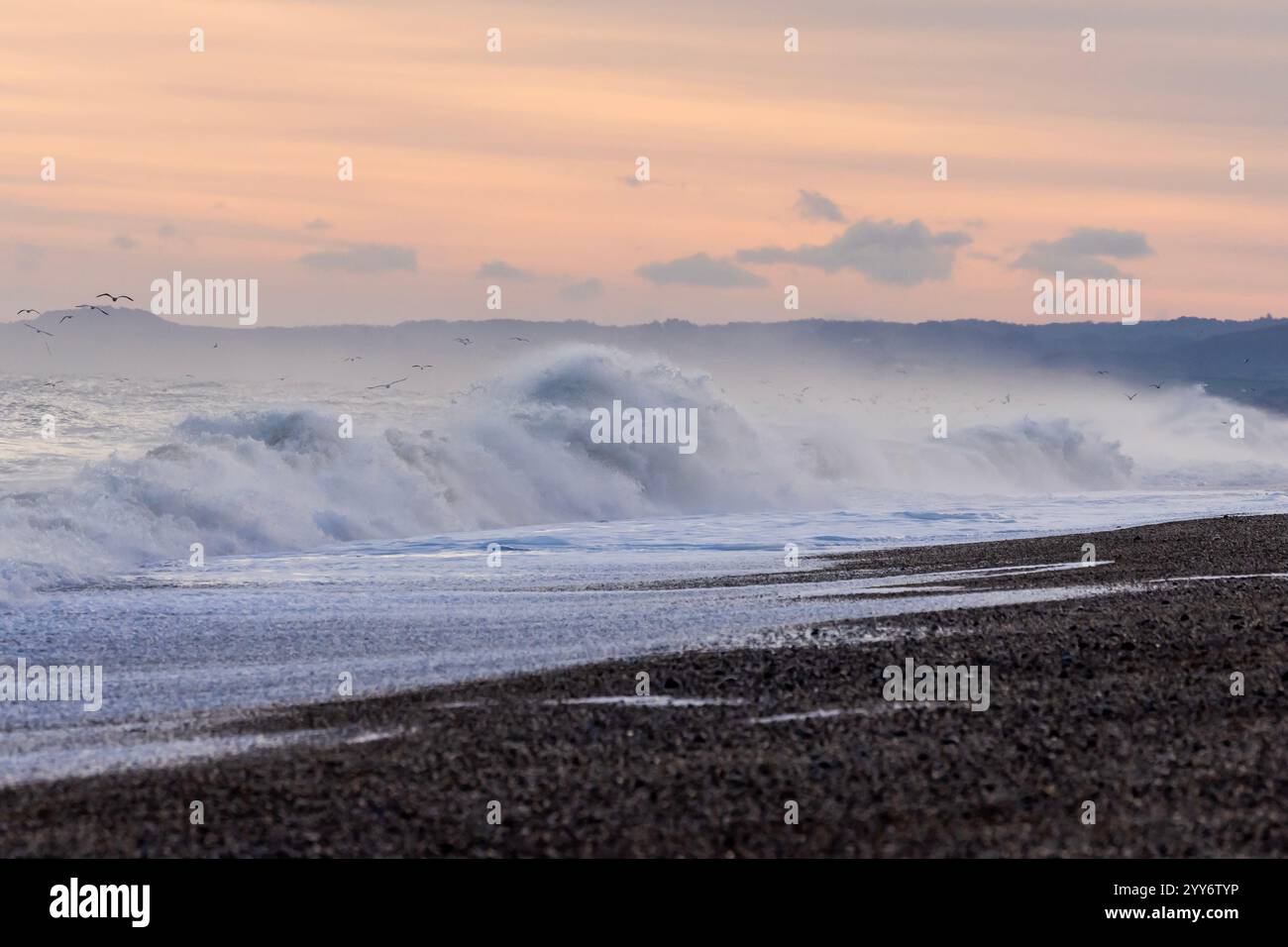 An einem kalten Wintermorgen an der Ostküste von Norfolk im Dezember krachen Flut-Wellen gegen den Kieselstrand von Cley Next Sea. Stockfoto