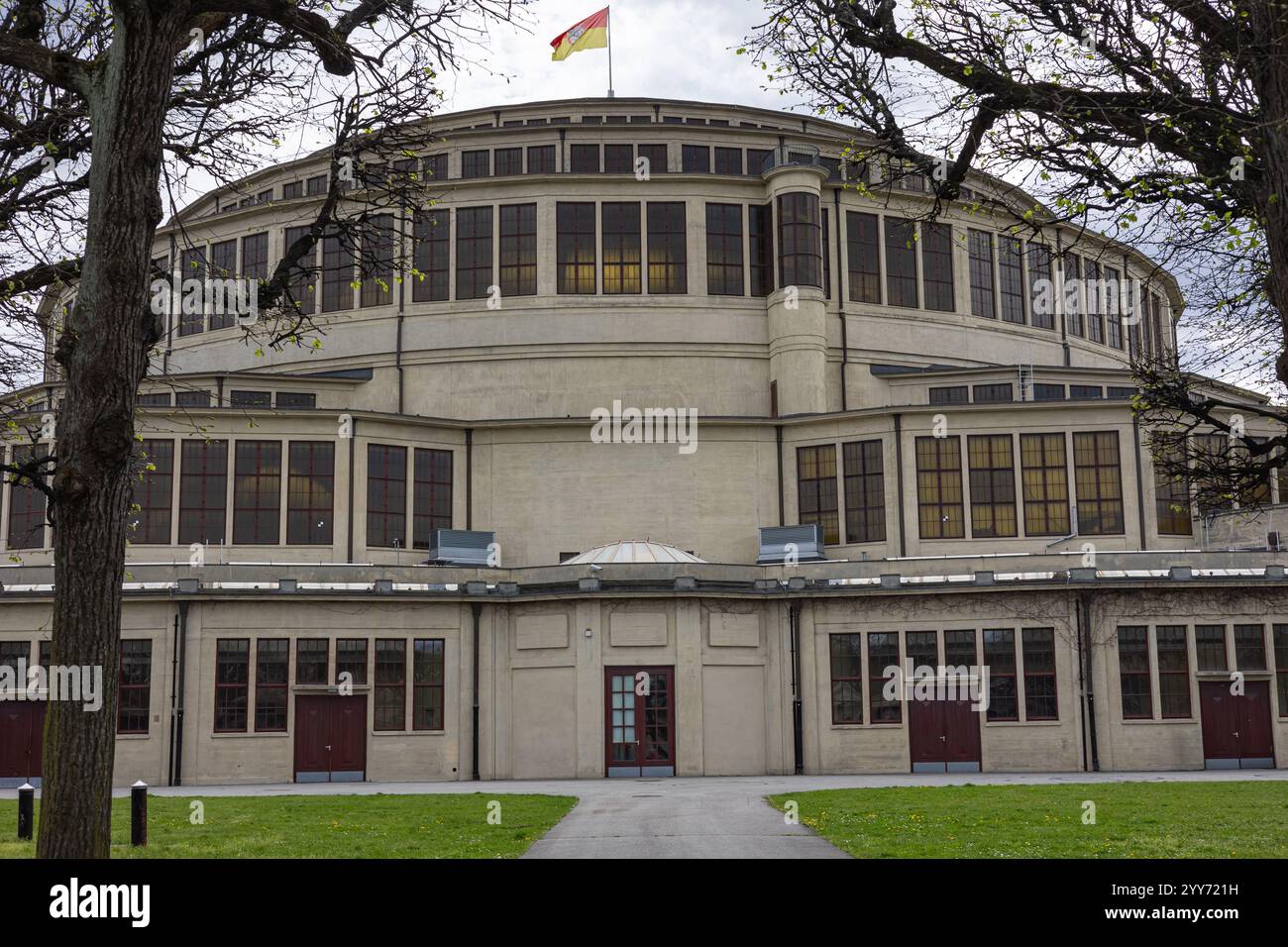 Historische Centennial Hall in Breslau, Polen, mit einzigartiger Architektur, großen Bogenfenstern und einer lebhaften Flagge auf dem Dach, umgeben von Bäumen Stockfoto