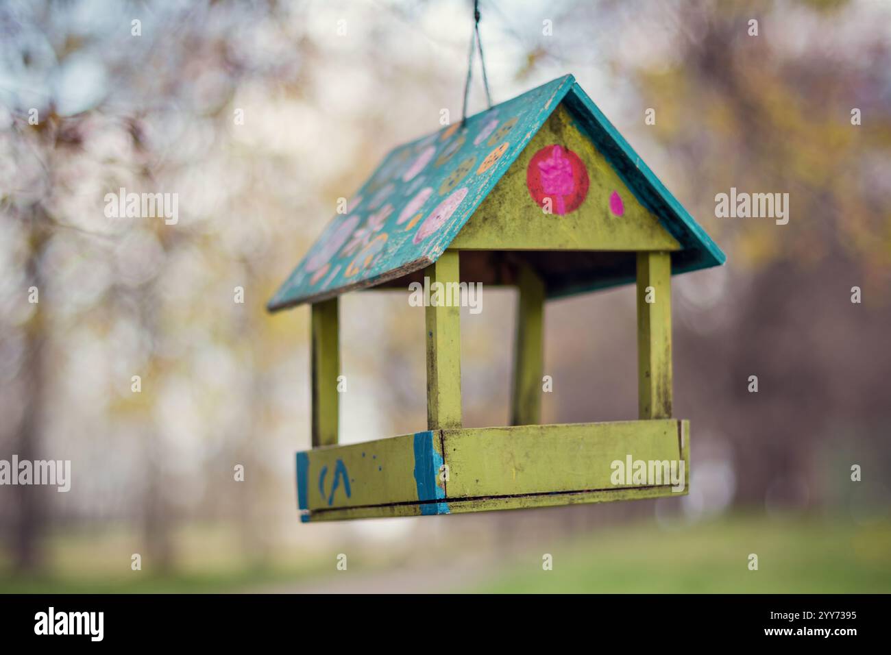 Farbenfrohes, handgefertigtes Vogelfutter (selektiver Fokus). Frühlingsblühender Garten im Hintergrund. Stockfoto
