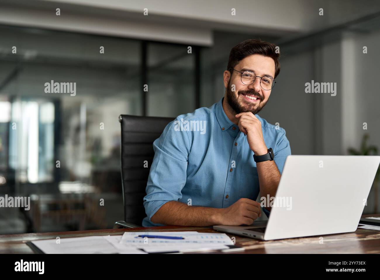 Porträt eines glücklichen Geschäftsmannes, der die Kamera im Büro betrachtet. Stockfoto