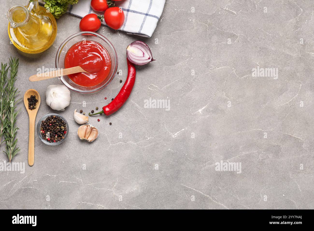 Komposition mit einer Schüssel Tomatenpaste, frischem Gemüse und Gewürzen auf Grunge-Hintergrund Stockfoto