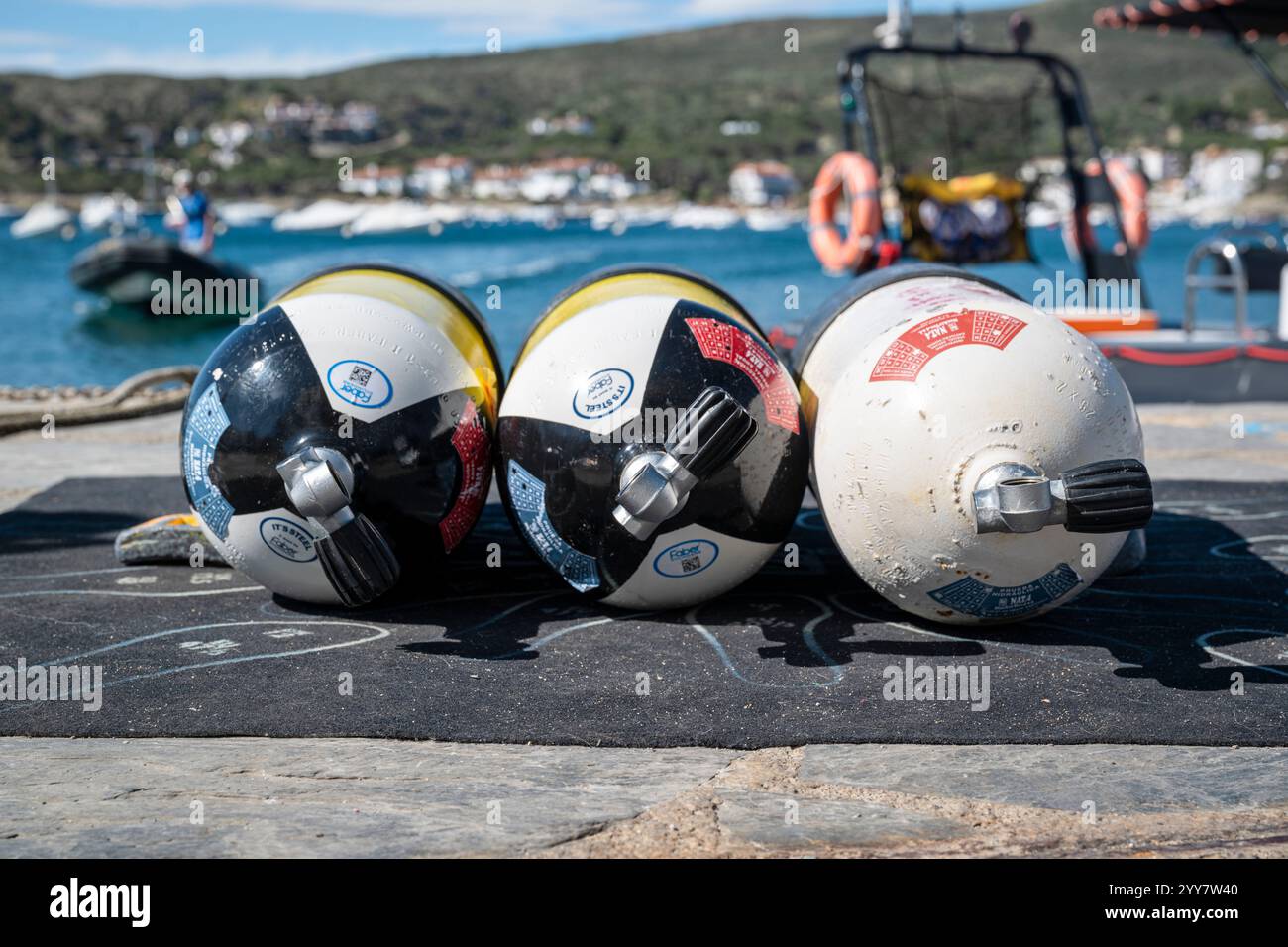 Drei Sauerstoffflaschen für Taucher liegen auf einer Matte an der Hafenmole in der Morgensonne von Cadaqués, Katalonien, Spanien Stockfoto