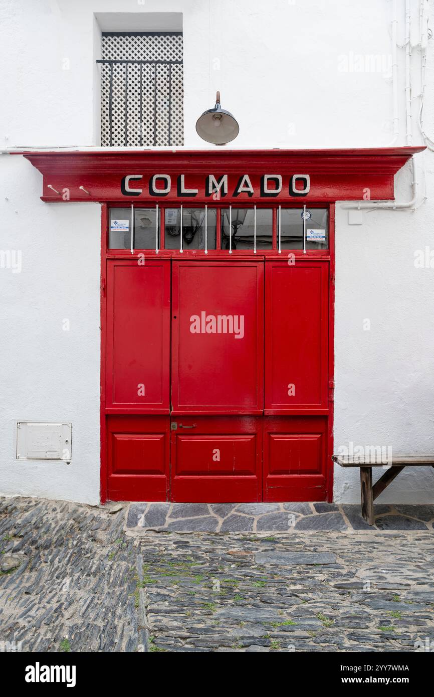 Geschlossene rote Holztür von einem Gemischtwarenladen in der Altstadt von Cadaqués, Katalonien, Spanien Stockfoto