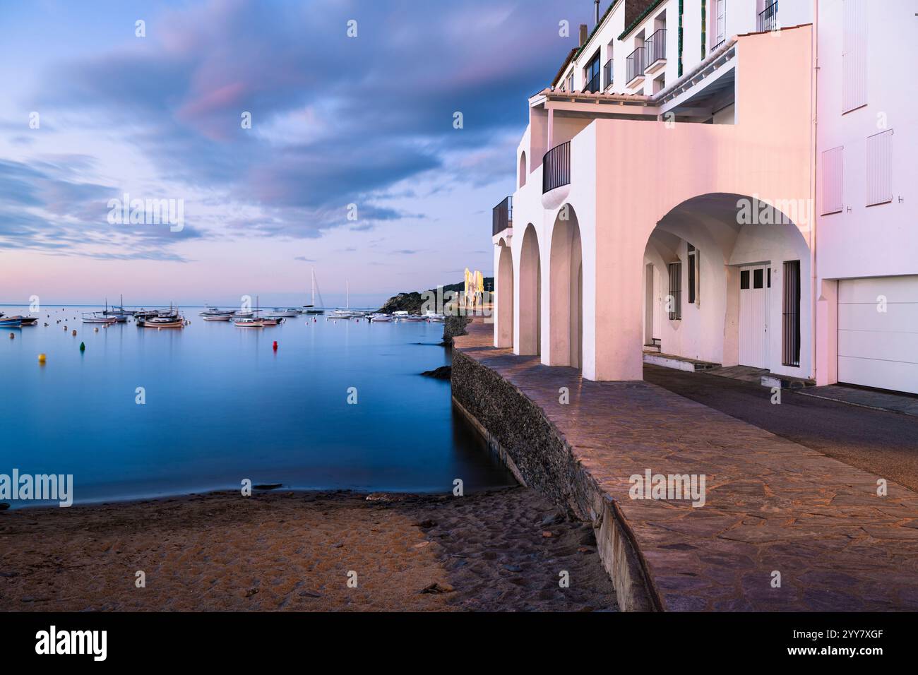 Die Fassaden der Häuser an der Hafenpromenade in der Altstadt von Cadaqués leuchten pastellfarben in der Morgendämmerung, Katalonien, Spanien Stockfoto