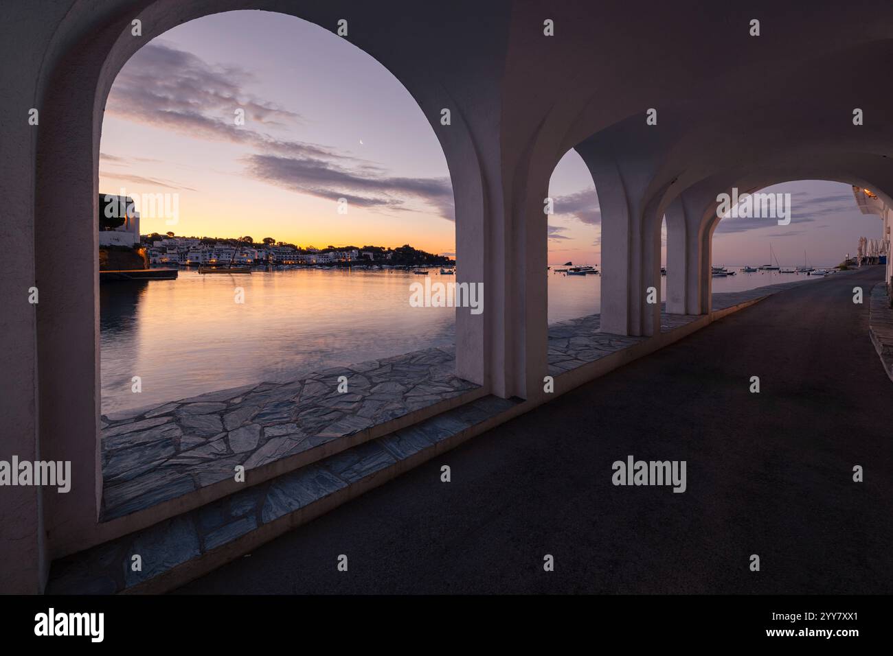 Arkaden an der Hafenpromenade in der Altstadt von Cadaqués leuchten pastellfarben in der Morgendämmerung, Katalonien, Spanien Stockfoto