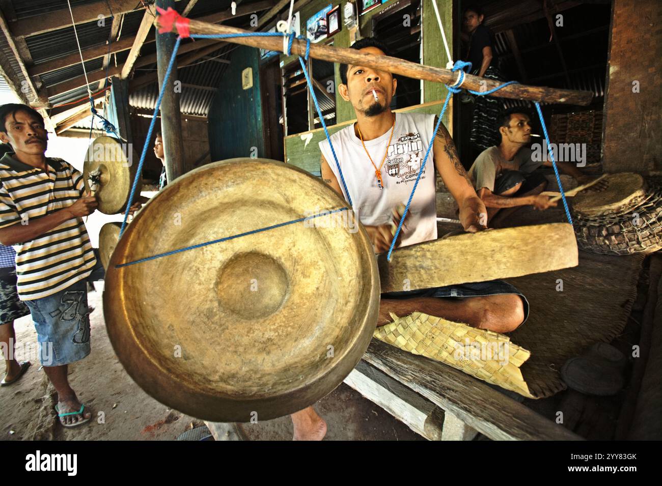 Männer, die während einer Trauersitzung Gongs spielten, als ein Mitglied ihrer Gemeinschaft, vergingen in Kilimbatu, Kawangu, Pandawai, East Sumba, East Nusa Tenggara, Indonesien. Gongs müssen nach dem lokalen Glaubenssystem (Marapu) gespielt werden, wenn jemand tot ist. Stockfoto