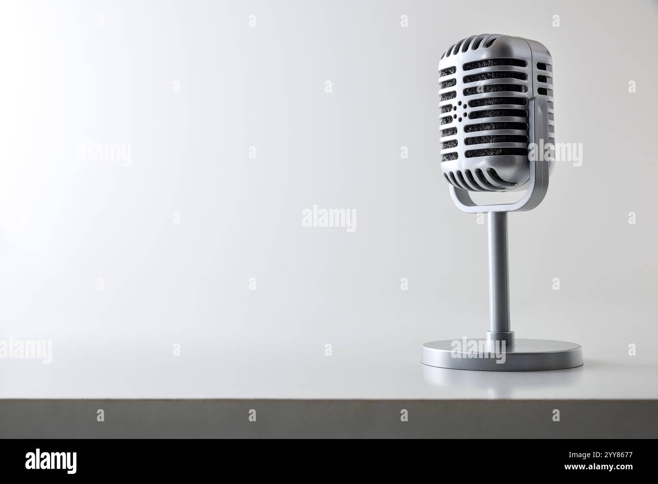 Hintergrund mit Metallkondensatormikrofon im Vintage-Stil mit Ständer auf weißem Tisch und Licht isoliertem Hintergrund. Schriftart-Ansicht. Stockfoto