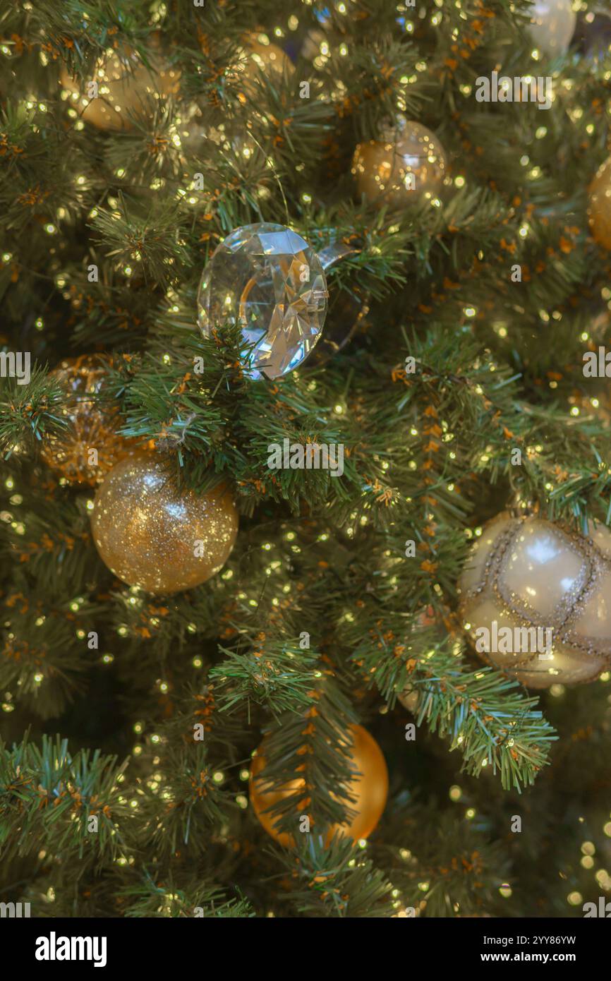Goldene Kugeln umgeben von leuchtenden Lichtern von Girlanden auf dem Weihnachtsbaum. Festlicher abstrakter Hintergrund. Stockfoto