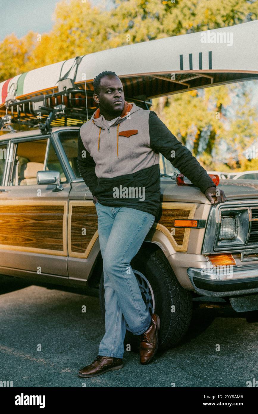 Der Mann steht neben einem Oldtimer mit Kanu und sieht ernst aus Stockfoto