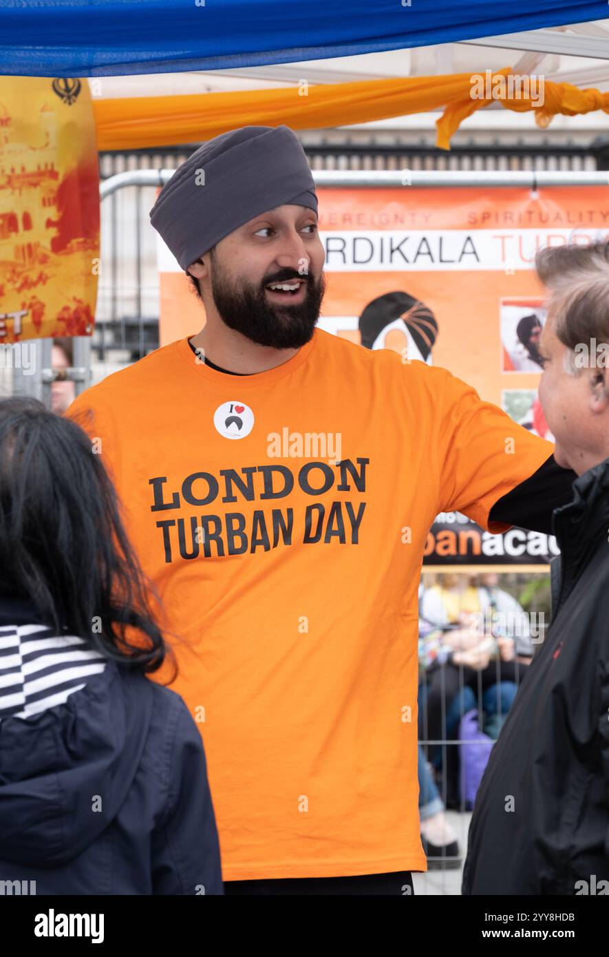 Fröhlicher Freiwilliger mit der Chardikala Turban Academy beim Vaisakhi Festival am Trafalgar Square, der Veranstaltung, die traditionelle Sikh-Kultur feiert. Stockfoto