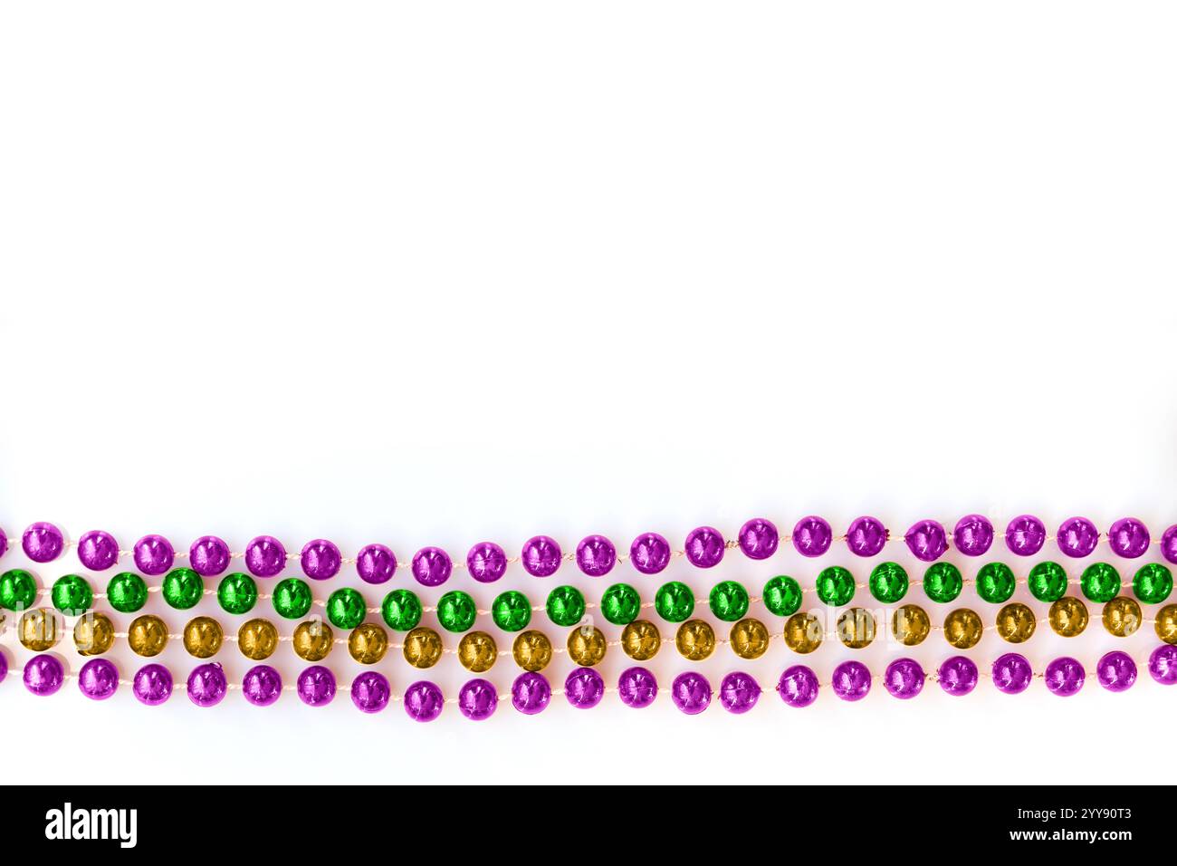 Mardi Gras Perlen in traditionellen lila, goldenen und grünen Farben isoliert auf weißem Hintergrund mit Kopierraum Stockfoto
