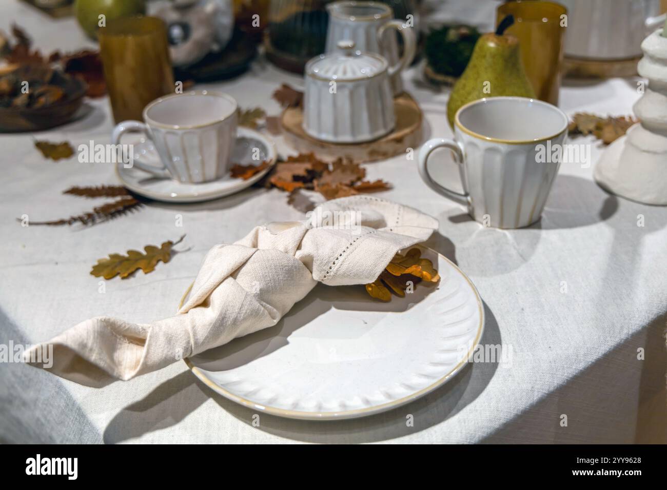 Ein wunderschön gestalteter Tisch, der für ein wunderbares Thanksgiving-Dinner mit Tellern, Tassen und ordentlich angeordneten Servietten für Gäste gedeckt ist Stockfoto