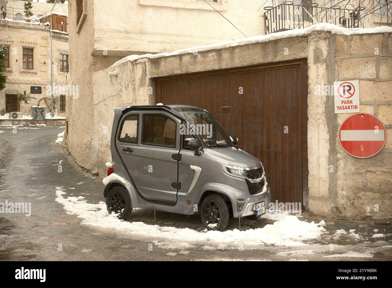 Göreme, Kappadokien, Türkiye : Ein kleines Elektroauto, Volta EV 1, mit einem kompakten und futuristischen Design, parkt an einer Ecke einer Gasse Stockfoto