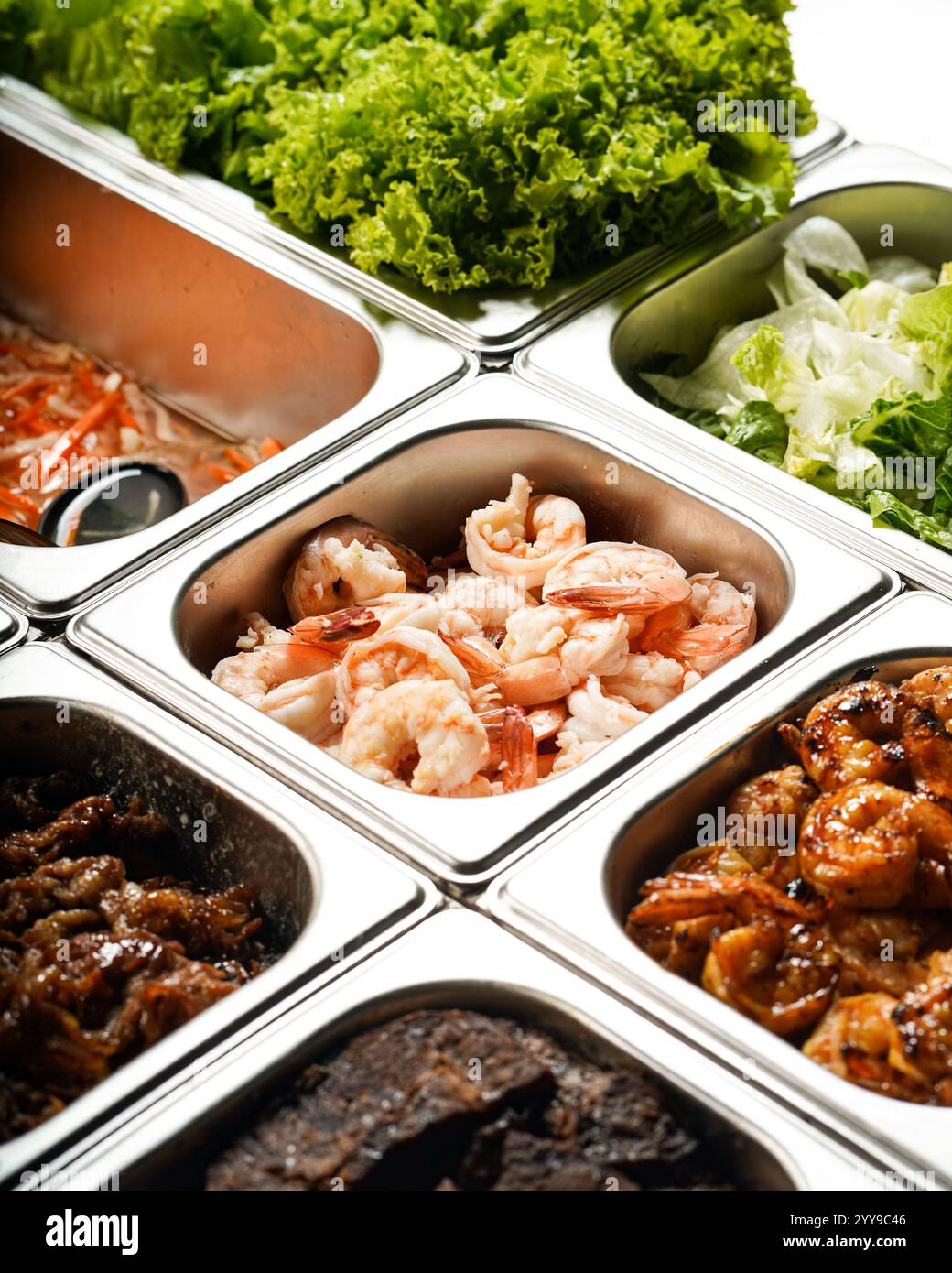 Ein lebhaftes Buffet mit verschiedenen frischen Zutaten, darunter gegrillte und gekochte Garnelen, mariniertes Fleisch, frischer Salat und Gemüse Stockfoto