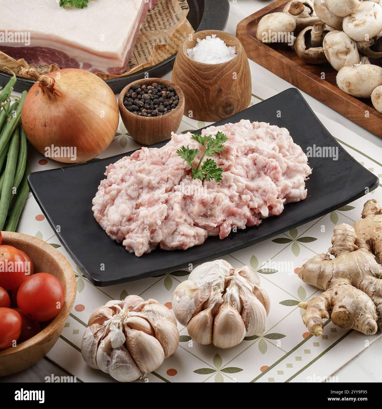 Eine rustikale Küchenszene mit frisch gemahlenem Schweinefleisch, umgeben von Bauerngemüse, aromatischen Gewürzen und natürlichen Zutaten, perfekt für hausgemachte Köche Stockfoto