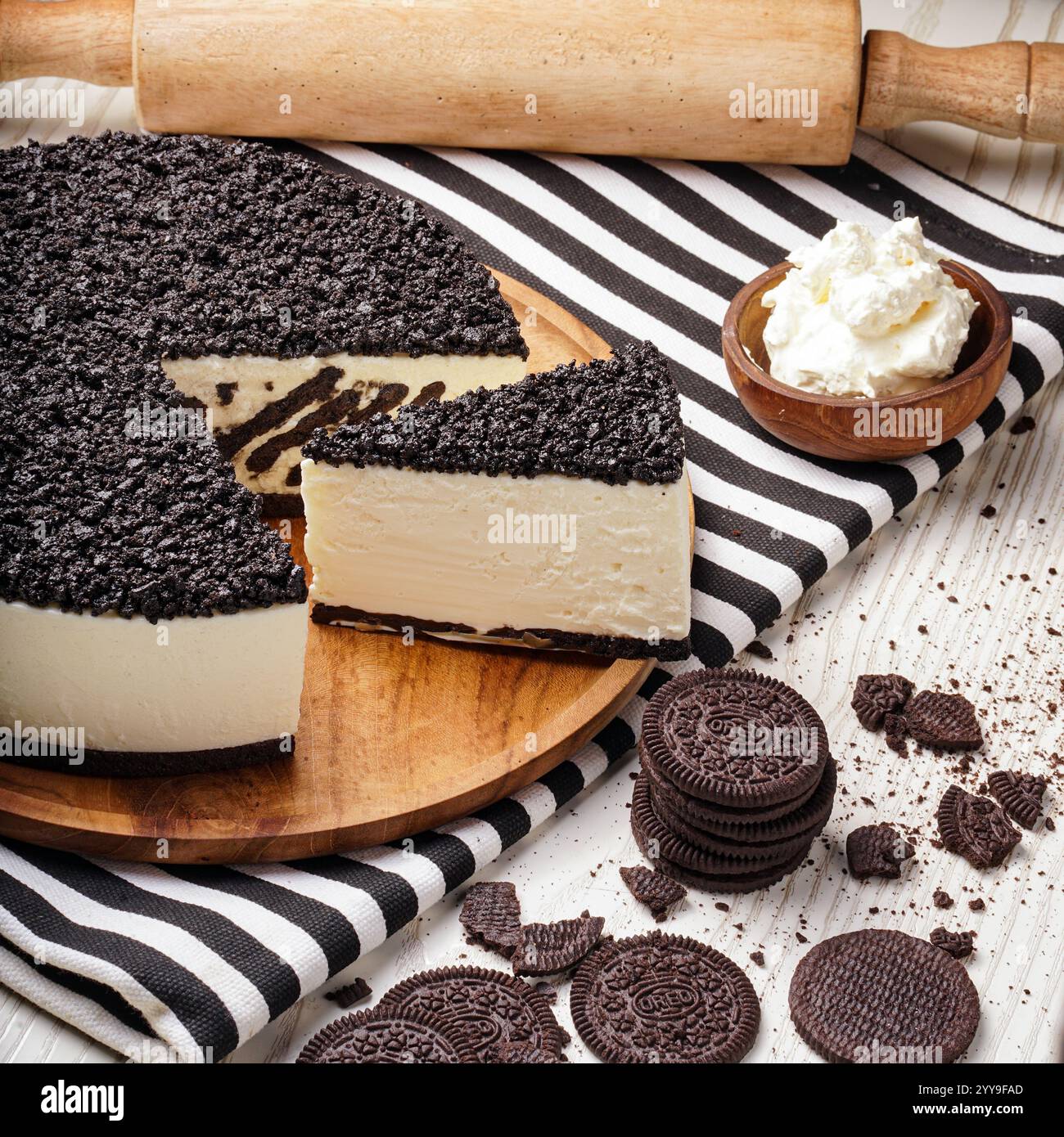 Ein wunderschön gestalteter Schokoladenmousse-Kuchen mit würfelförmigen Schokoladenschwammstücken, begleitet von Schlagsahne und umgeben von dunklem Choco Stockfoto