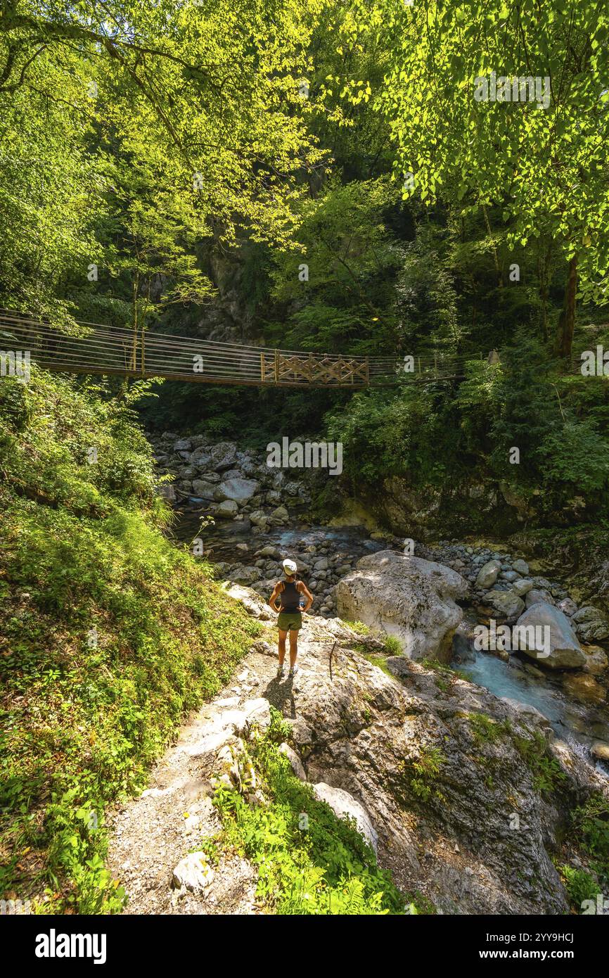 Weibliche Touristin genießt den atemberaubenden Blick auf den kristallklaren Fluss Zadlascica, der durch die tolmin Schlucht im triglav Nationalpark, slowenien fließt Stockfoto