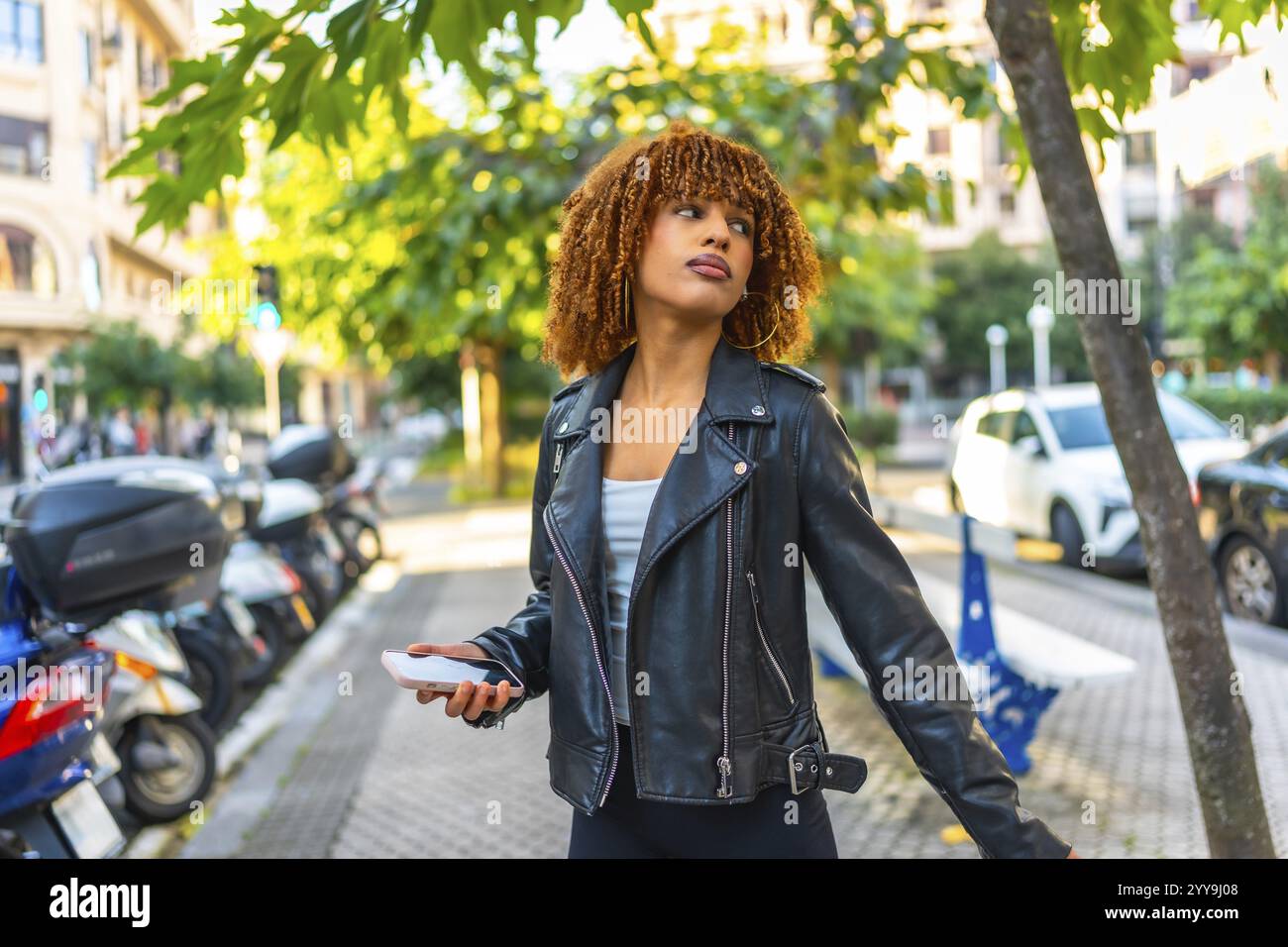 Seitenansicht einer hübschen, tausendjährigen lateinfrau, die Musik hört, die durch eine Stadt läuft Stockfoto