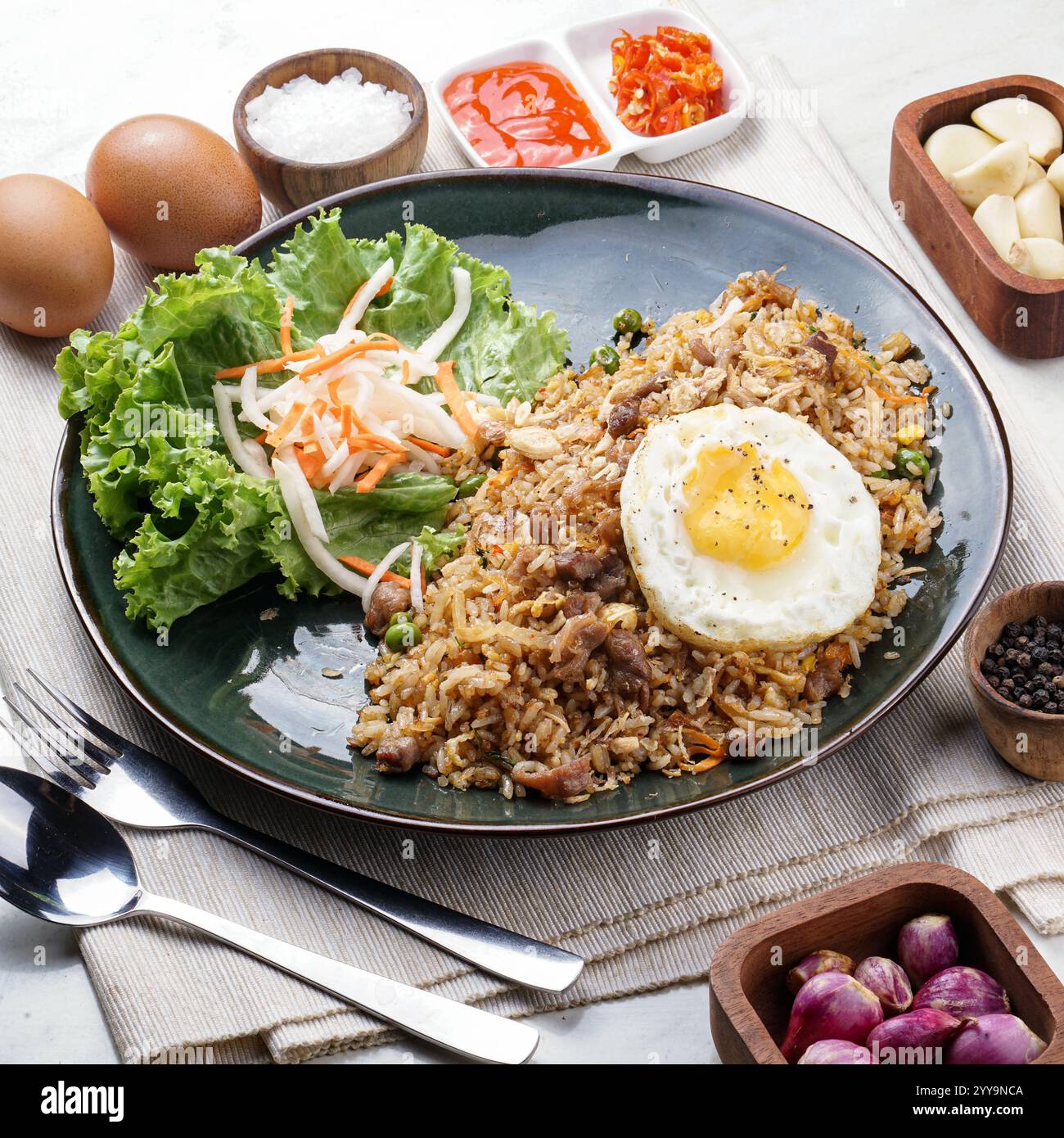 Ein lebhafter Teller vietnamesischer gebratener Reis auf einem Bananenblatt, der mit herzhaftem Geschmack, knusprigem Gemüse und aromatischen Kräutern gekrönt ist Stockfoto