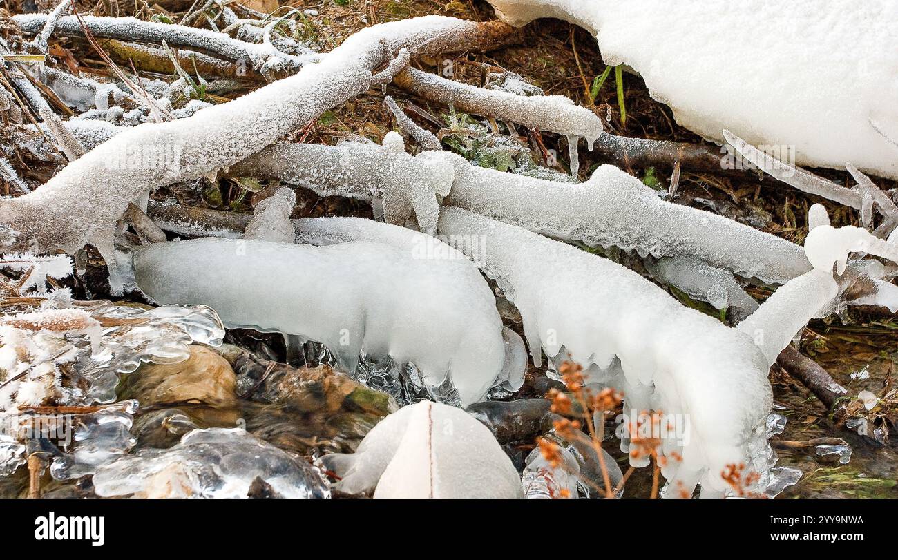 Wunderschön geformtes Eis, das einen Bach umschließt, mit mattierten Ästen und Schnee, fängt die Ruhe und Ruhe einer Winterlandschaft ein. Stockfoto