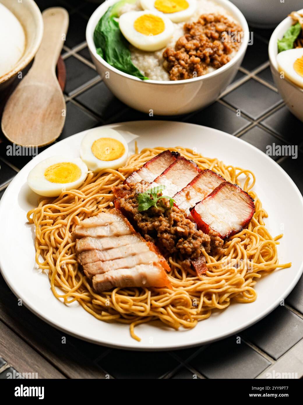 Traditionelles asiatisches Nudelgericht mit knusprigen Schweinebauchscheiben, Hackfleisch, hartgekochten Eiern und einer Beilage Fischkugelsuppe Stockfoto