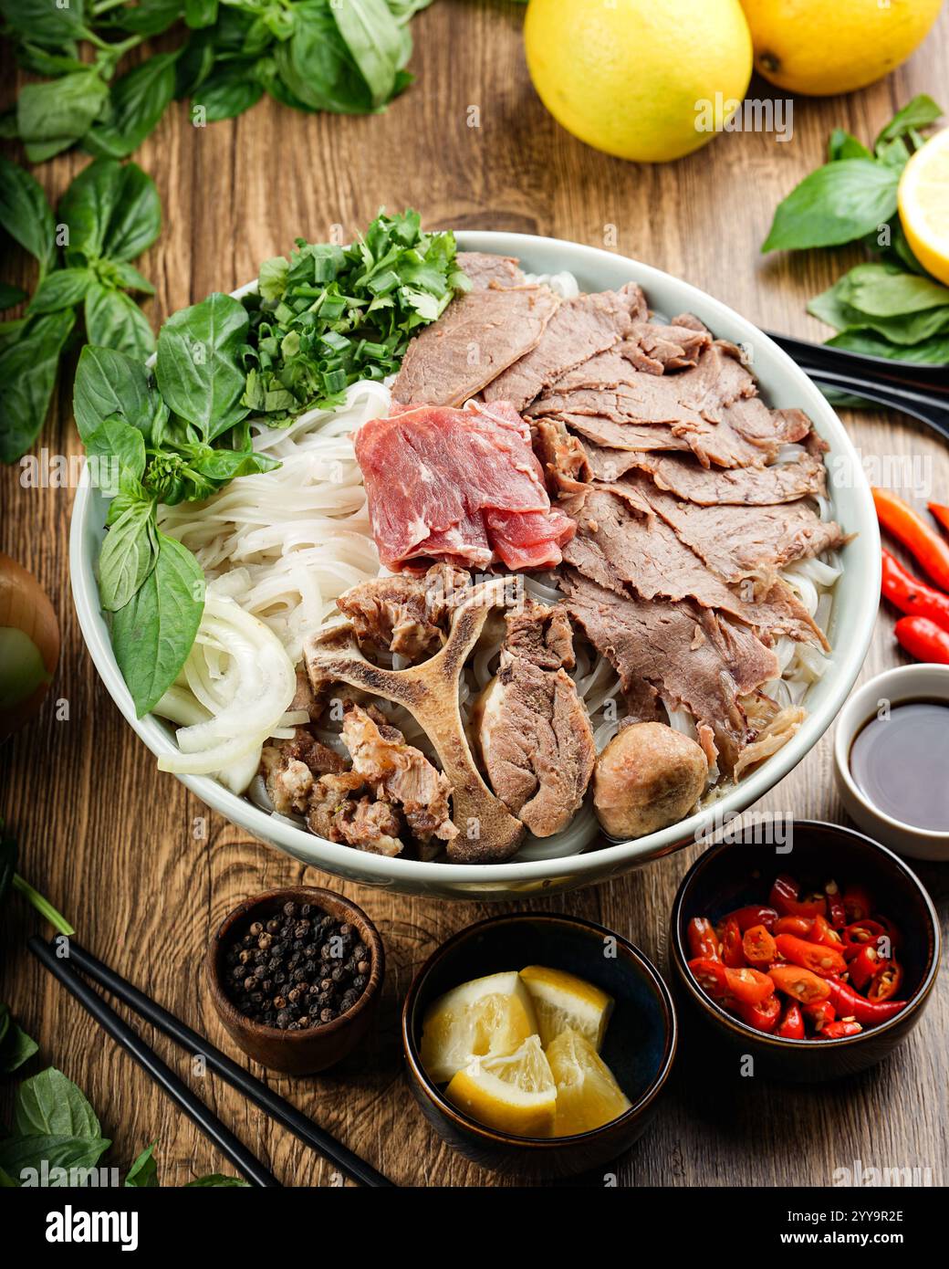 Eine vibrierende Schüssel mit scharfer vietnamesischer Rindfleischnudelsuppe (bún Bò Huế), die mit frischen Kräutern, Chili und zarten Rindfleischscheiben gefüllt ist, ein authentischer Geschmack von Vietnam Stockfoto