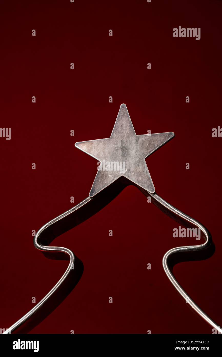 Metall-weihnachtsbaumdekoration mit Stern auf einem burgunderroten Hintergrund mit Kopierraum, Platz für Text Stockfoto