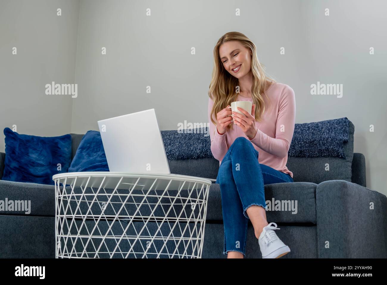 Eine junge, schöne Frau sitzt ruhig zu Hause und organisiert ihren Tag mit ihrer Elektronik. Umgeben von Ruhe gleicht sie Konzentration und Entspannung aus, Prepa Stockfoto