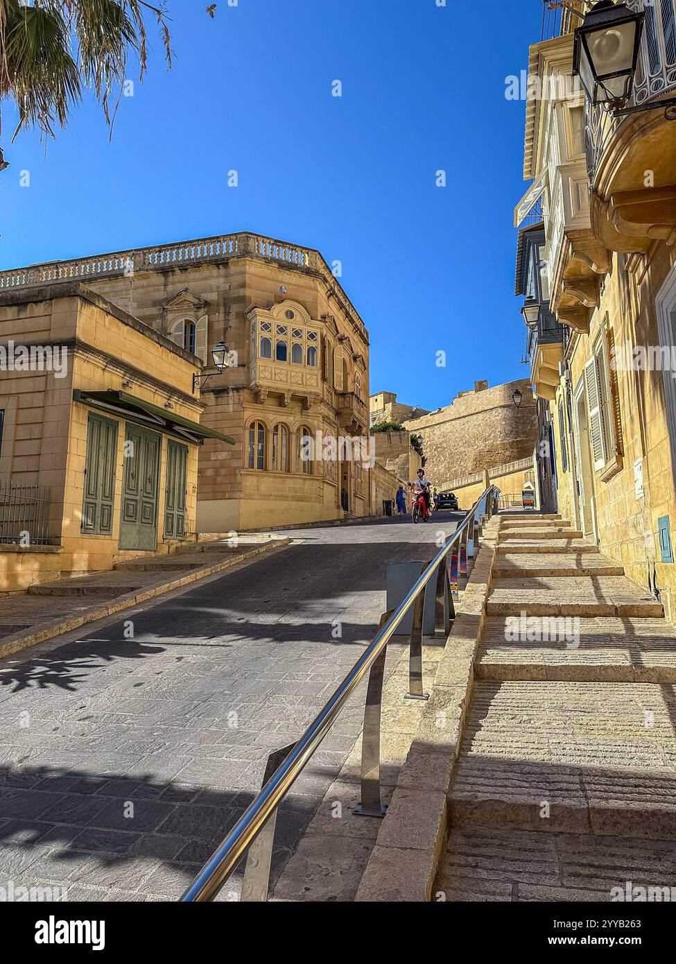 Victoria, Gozo, Malta - 8. Juni 2024: Historische Häuser mit Holzbogenfenstern und Terrassen in einer engen Straße in Victoria City auf Gozo Island, Malta Stockfoto