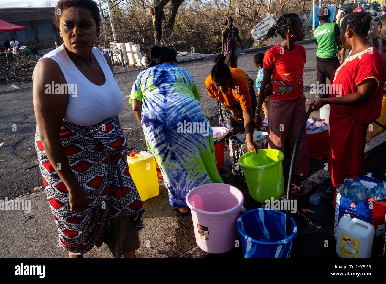 Paris, Frankreich. Dezember 2024. Michael Bunel/Le Pictorium - MAYOTTE, Zyklon Chido - 20/12/2024 - Frankreich/Paris - Frauen und Kinder sammelten Wasser aus einem Wasserhahn, der zwei Tage nach Zyklon Chido in Betrieb genommen wurde. Die Insel ist verwüstet nach dem Durchzug des Zyklons Chido, der am 14. Dezember die Insel Mayotte traf. Die bereits vor dem Wirbelsturm verarmte Bevölkerung beklagte sich über mangelnde Erleichterung. Dezember 2024. Mamoudzou, Mayotte. Quelle: LE PICTORIUM/Alamy Live News Stockfoto