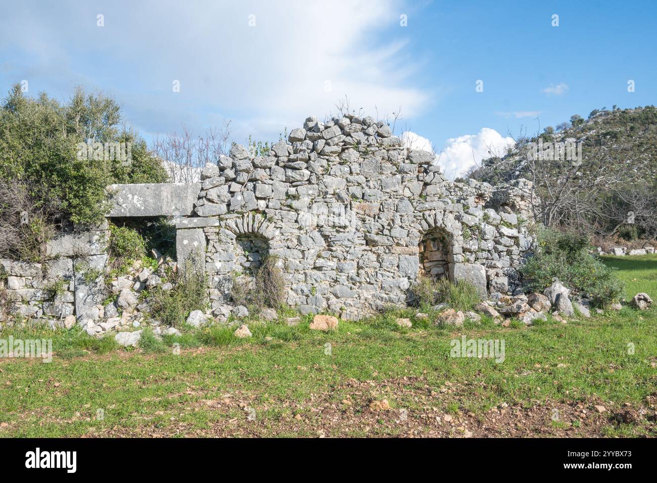 Antike römische Struktur in Sidyma turkey, hitorische Stätte am lykischen Weg, Steinstruktur steht inmitten eines üppigen grünen Feldes, Stockfoto