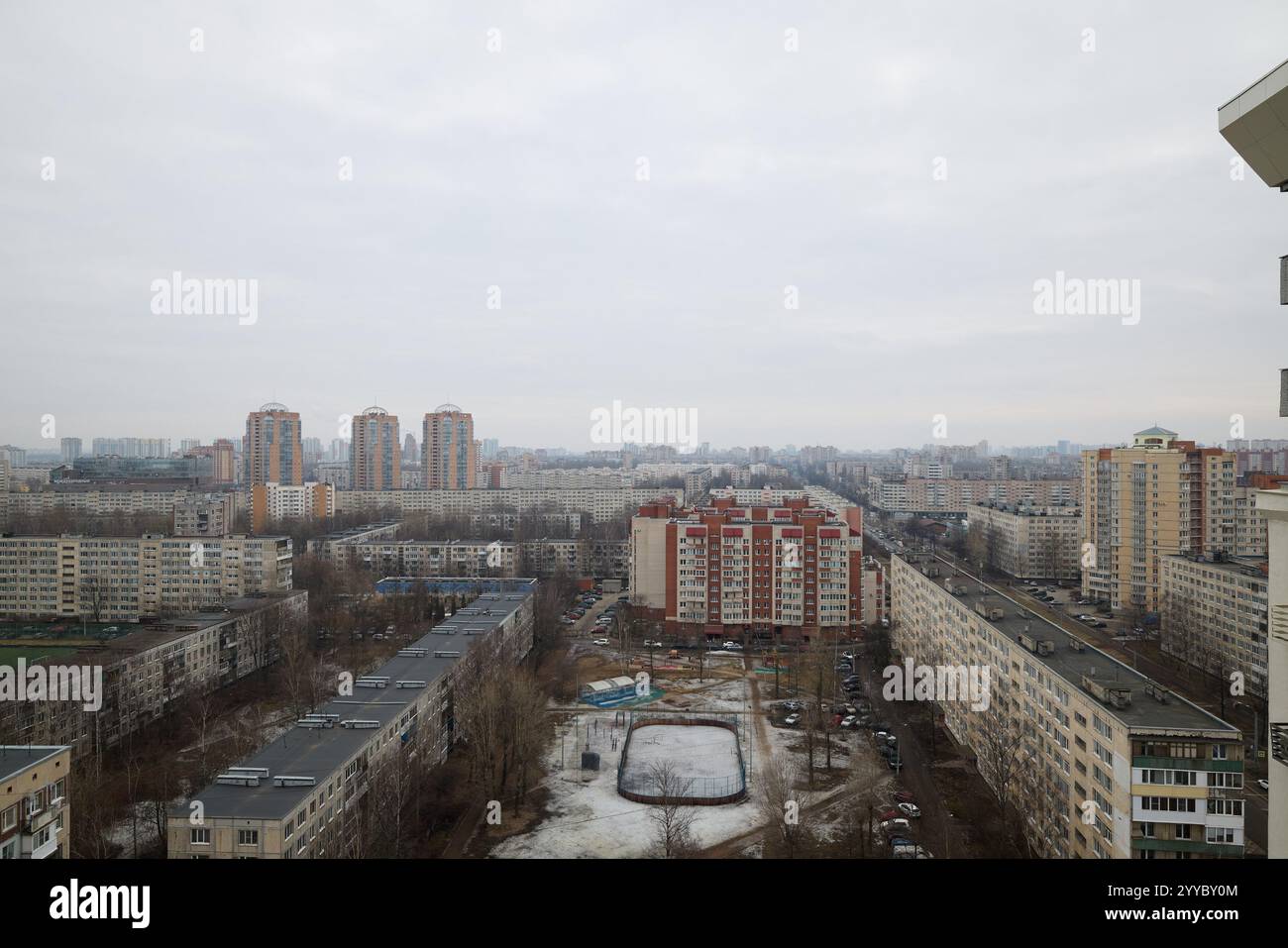 Ein Panoramablick auf ein weitläufiges Stadtgebiet unter grauem Himmel mit Wohngebäuden und leerstehenden Flächen. Stockfoto