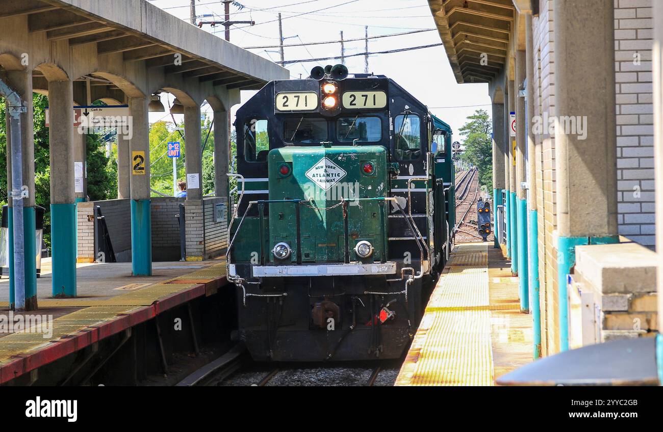 Babylon, New York, USA - 20. August 2024: Ein Zug hält an einem stark frequentierten Bahnhof an, während sich die Passagiere an einem klaren und hellen Tag auf das Einsteigen vorbereiten. Stockfoto