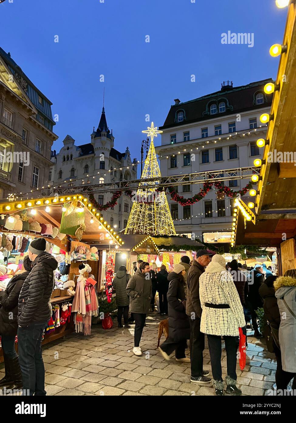 Weihnachtsmarkt am Hof im Zentrum von Wien mit beleuchtetem Weihnachtsbaum, Marktständen und Menschen. Am Abend in der Dämmerung aufgenommen. Stockfoto