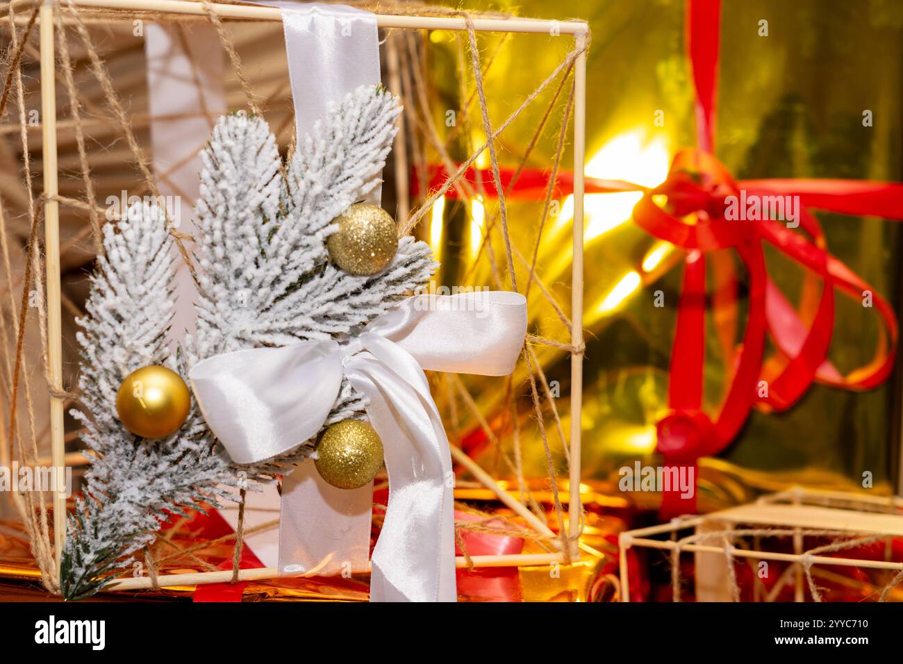 Die raffinierte Weihnachtsdekoration zeigt einen Holzrahmen, der mit Tannenzweigen, Ornamenten und Bändern in der Nähe wunderschön gewickelter Geschenke verziert ist und eine warme Atmosphäre schafft Stockfoto