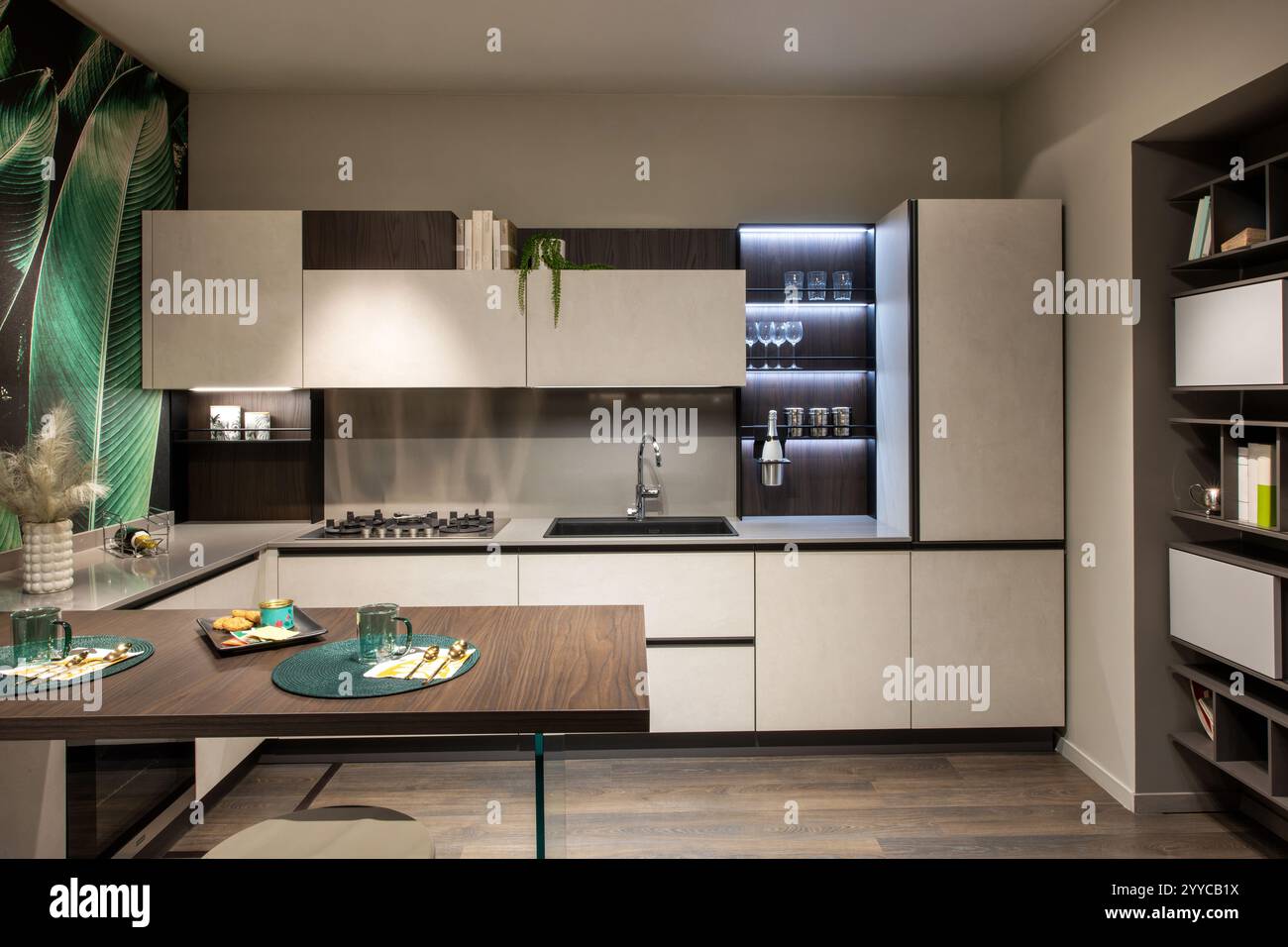 Moderne und stilvolle Küche mit weißen und braunen Schränken, Insel- und tropischen Tapeten, mit zeitgenössischem Innendesign Stockfoto
