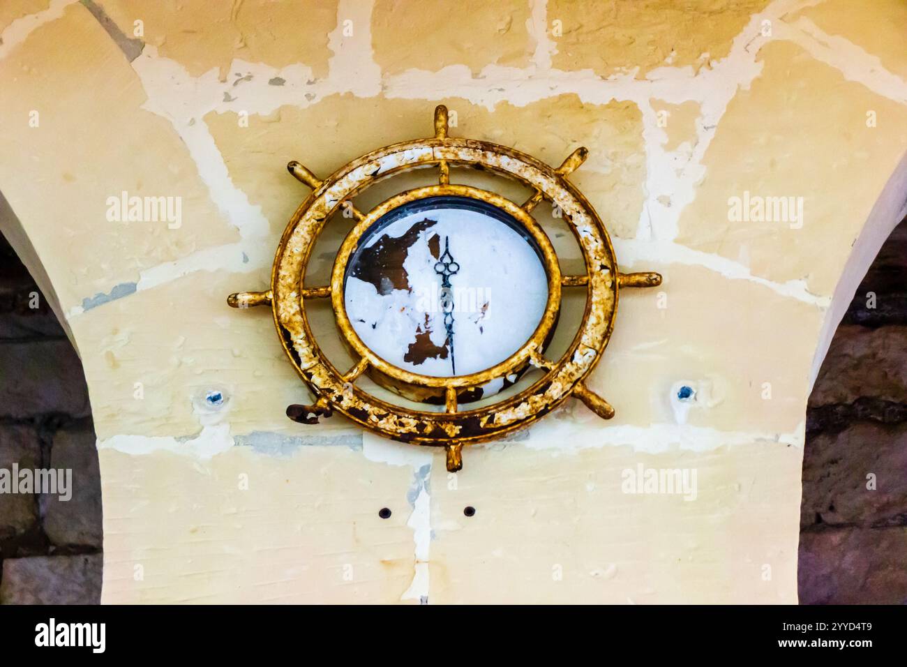 Rustikale Schiffsraduhr an strukturierter Wand mit einzigartigem ästhetischem Design Stockfoto