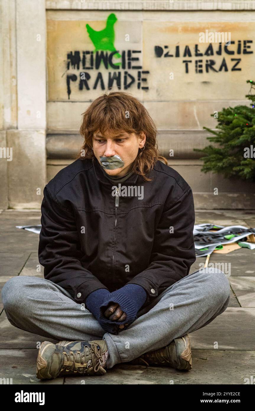 Ein Demonstrant mit aufgeklebtem Mund, unter schablonierten Slogans, die auf Polnisch "Sprechen Sie die Wahrheit" und "handeln Sie jetzt" während der Kundgebung sagen. Aktivisten der Gruppe Animal Rebellion sprühten und malten ihre Forderungen an die Wände des Ministeriums für Landwirtschaft und ländliche Entwicklung in Warschau, befestigten ein Manifest am Tor und warteten dann mit geschlossenen Mündern still auf das Eintreffen der Polizei. Die polnische Tieraufstandsgruppe erklärte, dass alle Materialien, die für den Protest verwendet werden, leicht abwaschbar und nicht dauerhaft sind. Ziel der Aktion ist es, die Aufmerksamkeit auf das Leiden von Tieren und zu lenken Stockfoto