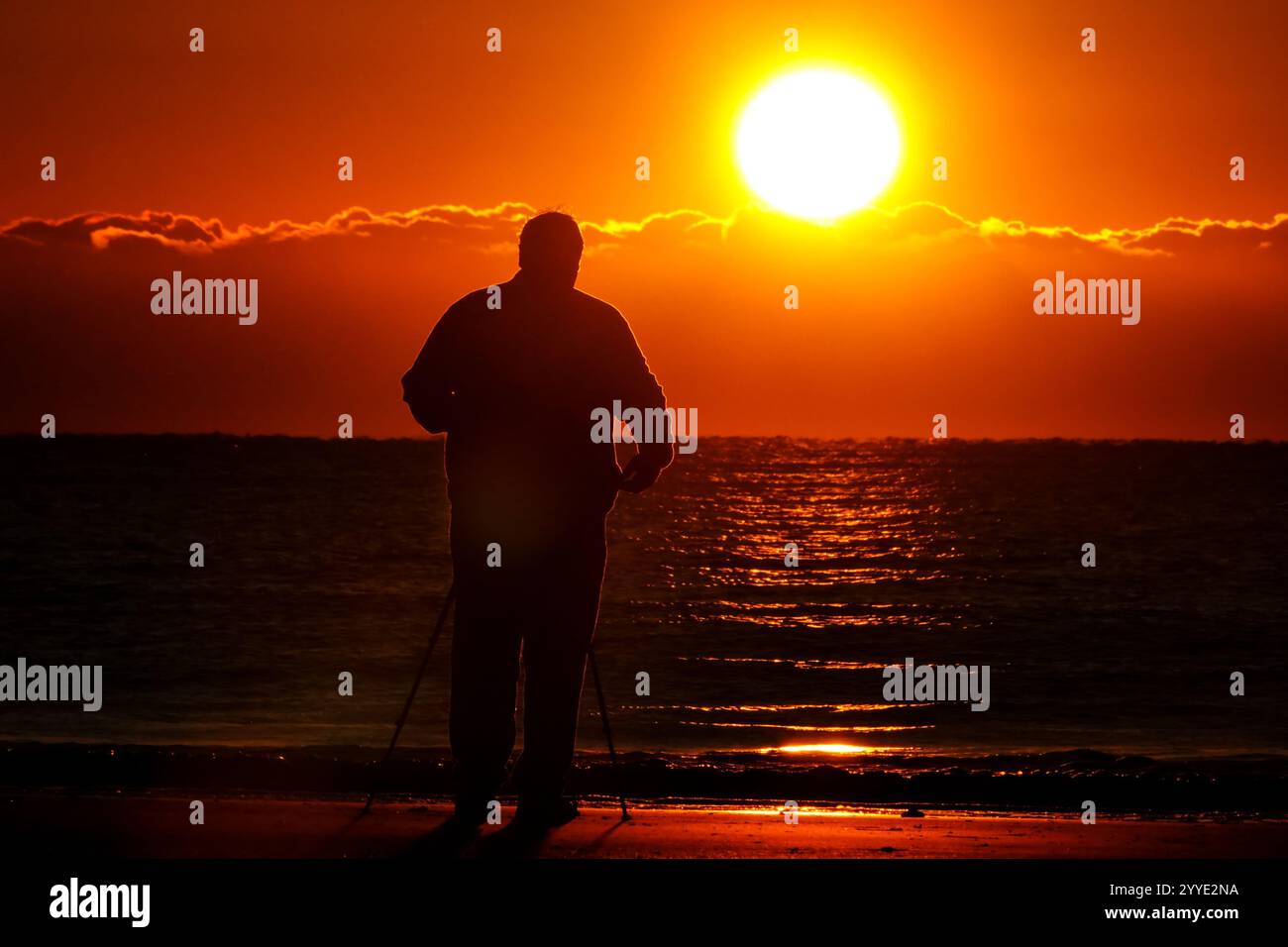 Isle Of Palms, Usa. Dezember 2024. Ein Fotograf fotografiert den Sonnenaufgang an einem kalten Morgen zur Wintersonnenwende vom Isle of Palms Pier, 21. Dezember 2024 in Isle of Palms, South Carolina. Die Wintersonnenwende ist der kürzeste Tag der nördlichen Hemisphäre und markiert den Beginn des Winters. Quelle: Richard Ellis/Richard Ellis/Alamy Live News Stockfoto