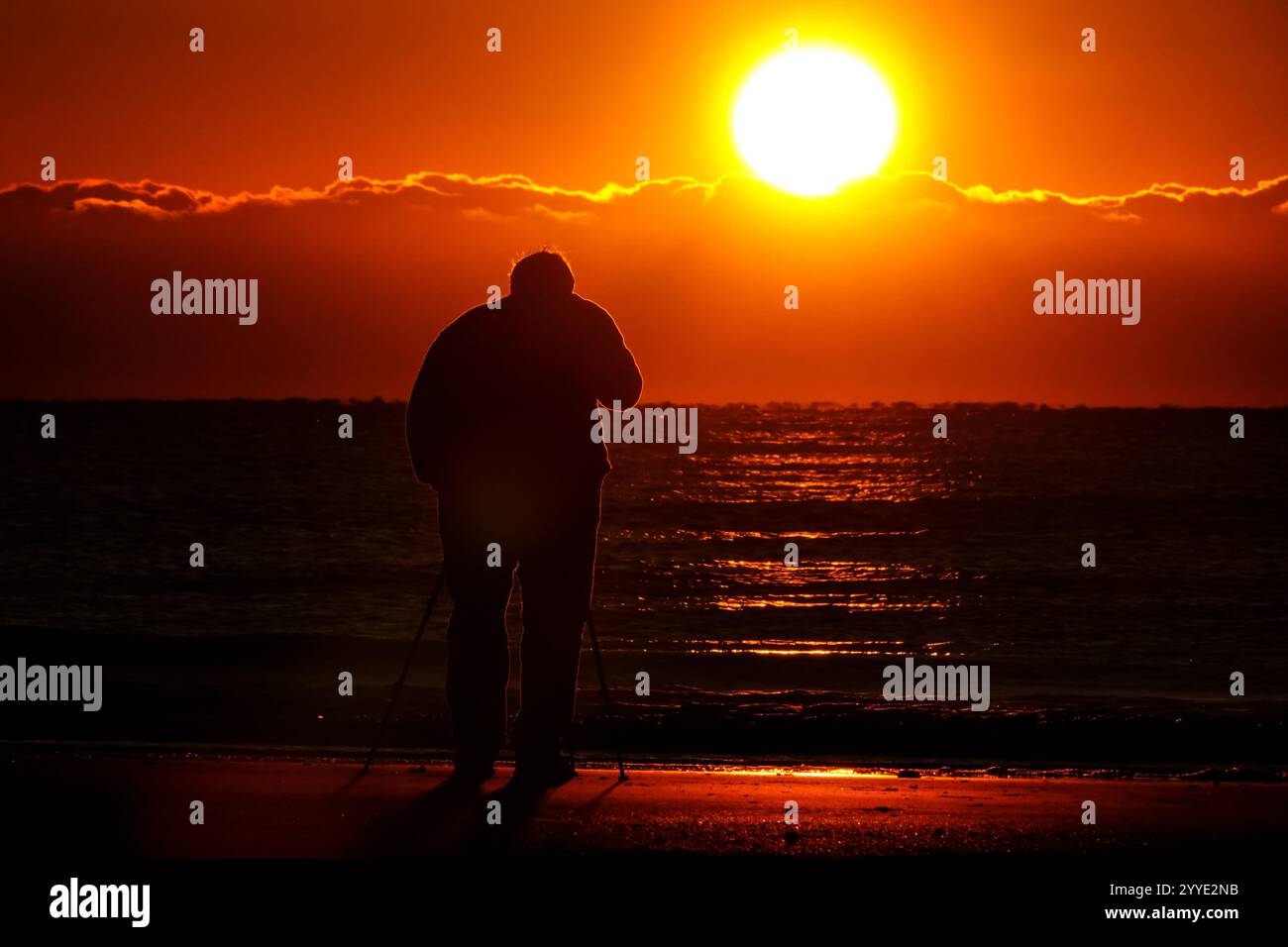 Isle Of Palms, Usa. Dezember 2024. Ein Fotograf fotografiert den Sonnenaufgang an einem kalten Morgen zur Wintersonnenwende vom Isle of Palms Pier, 21. Dezember 2024 in Isle of Palms, South Carolina. Die Wintersonnenwende ist der kürzeste Tag der nördlichen Hemisphäre und markiert den Beginn des Winters. Quelle: Richard Ellis/Richard Ellis/Alamy Live News Stockfoto