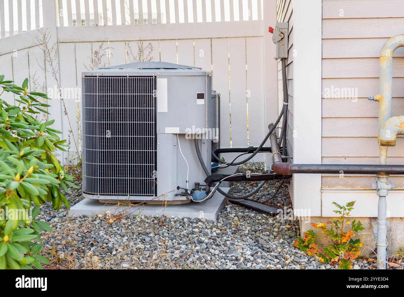 Klimaanlagen-Außeneinheit an einem Holzzaun in einem Haus im Hinterhof Stockfoto