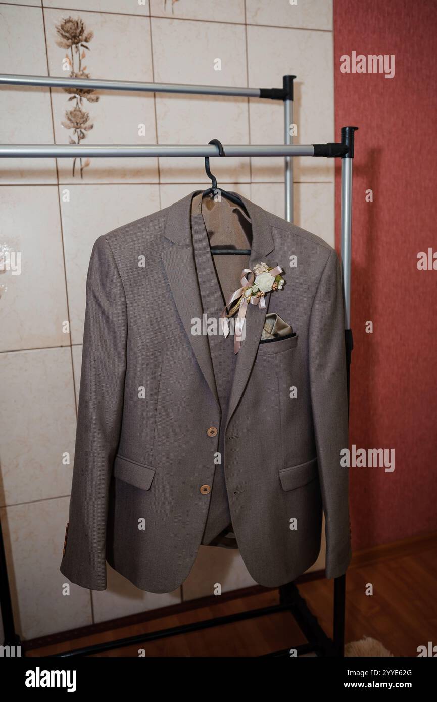 Eleganter grauer Anzug mit Blumenboutonniere auf dem Bügel. Stockfoto