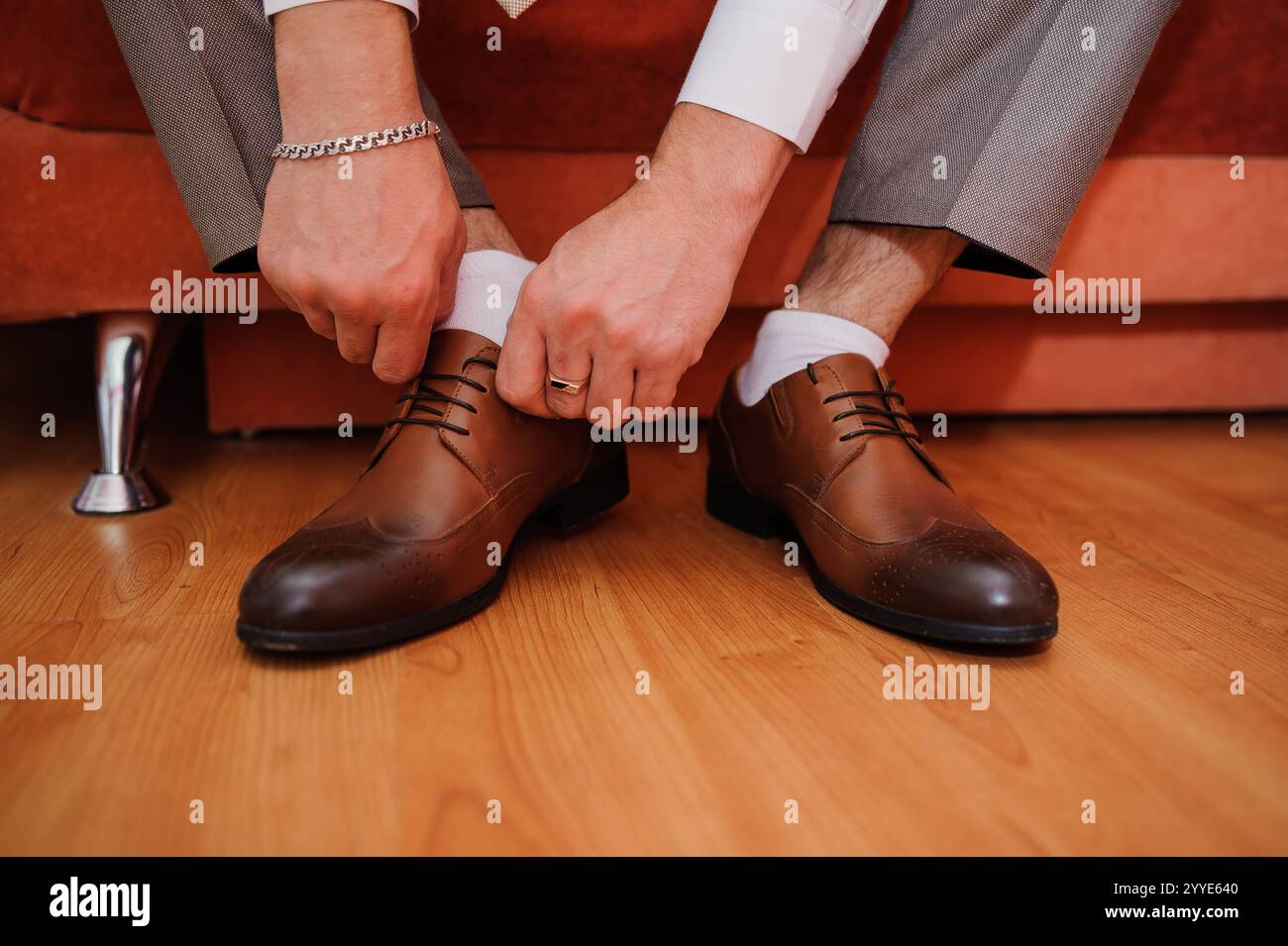 Vorbereitung auf ein formelles Ereignis: Ein Mann, der seine braunen Schuhe bindet. Stockfoto