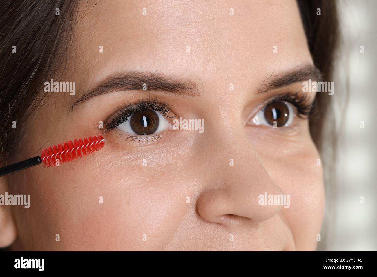 Wimpernverlängerungsverfahren. Frau kämmt Wimpern mit Bürste, Nahaufnahme Stockfoto