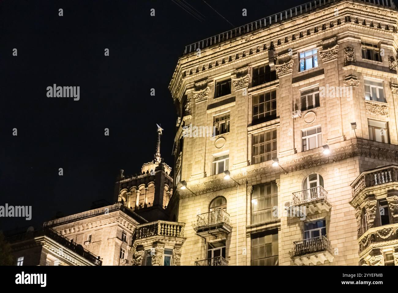 Ein großes Gebäude mit vielen Fenstern und Balkon. Das Gebäude ist nachts beleuchtet Stockfoto