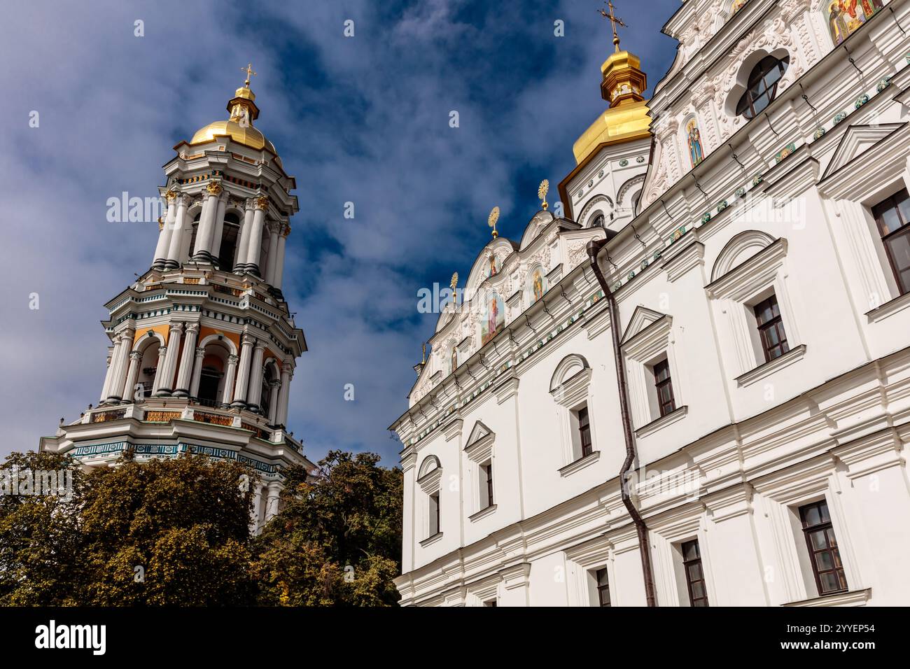 Ein großes weißes Gebäude mit einer goldenen Kuppel und einem Uhrenturm. Das Gebäude ist von Bäumen umgeben und hat eine friedliche, ruhige Atmosphäre Stockfoto