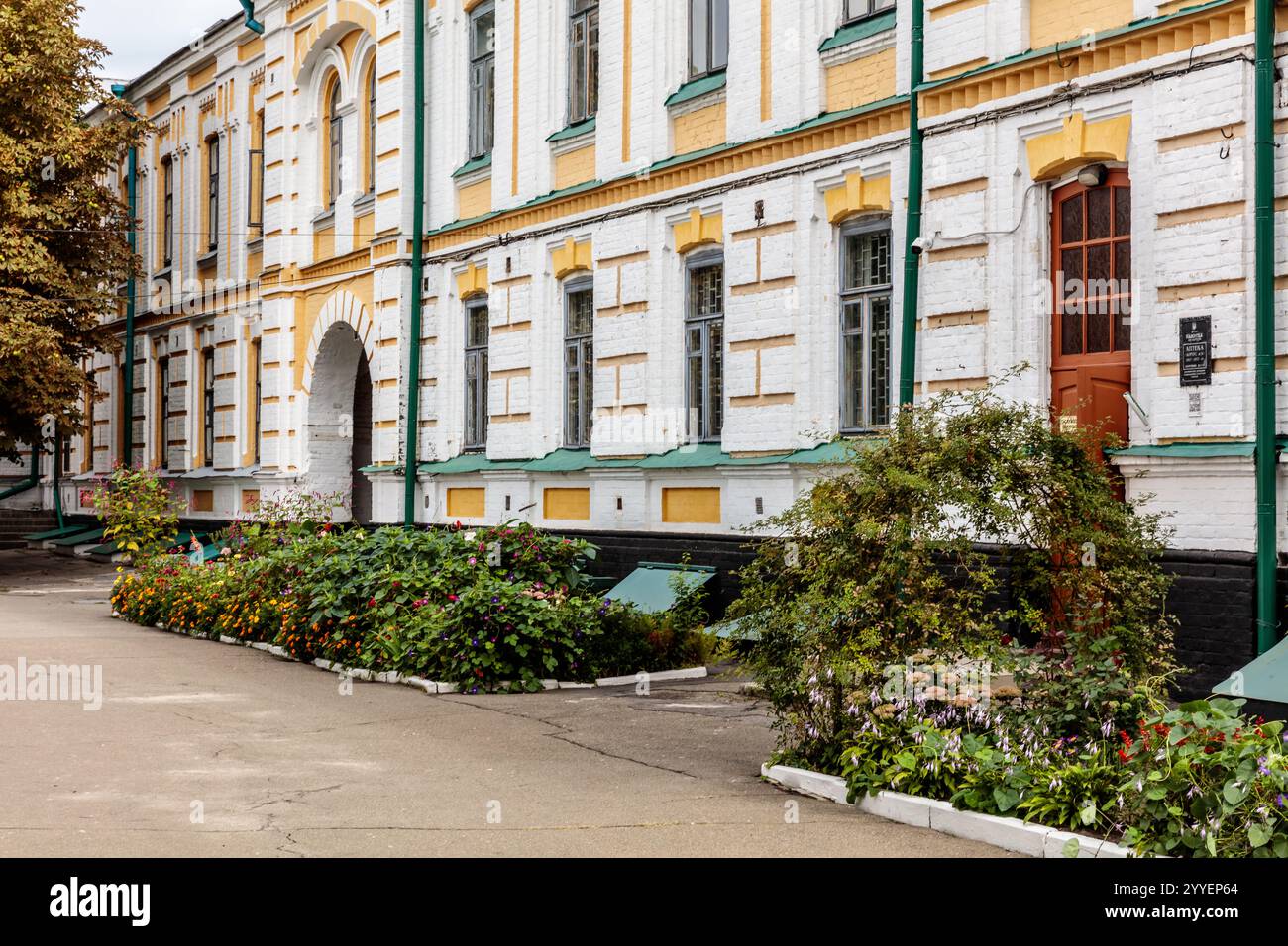 Ein großes Gebäude mit einem grünen Dach und einer weißen Fassade. Das Gebäude hat einen großen Torbogen und eine rote Tür. Die Vorderseite des Gebäudes hat einen großen grünen Bu Stockfoto