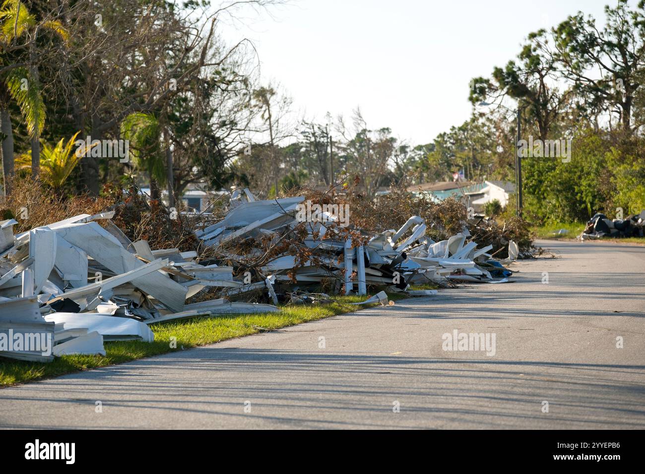Müllhaufen auf der Straßenseite von stark beschädigten Häusern nach dem Hurrikan in Florida Wohnmobilgebiet. Folgen von Naturkatastrophen Stockfoto