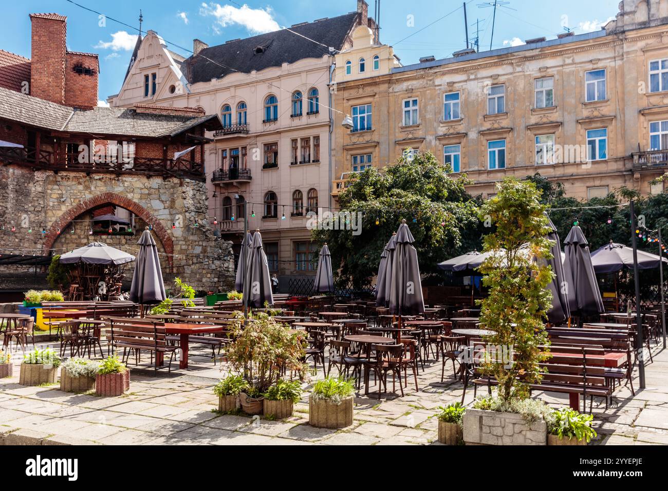 Ein Stadtplatz mit vielen Tischen und Stühlen und vielen Sonnenschirmen. Die Atmosphäre ist lebhaft und einladend Stockfoto