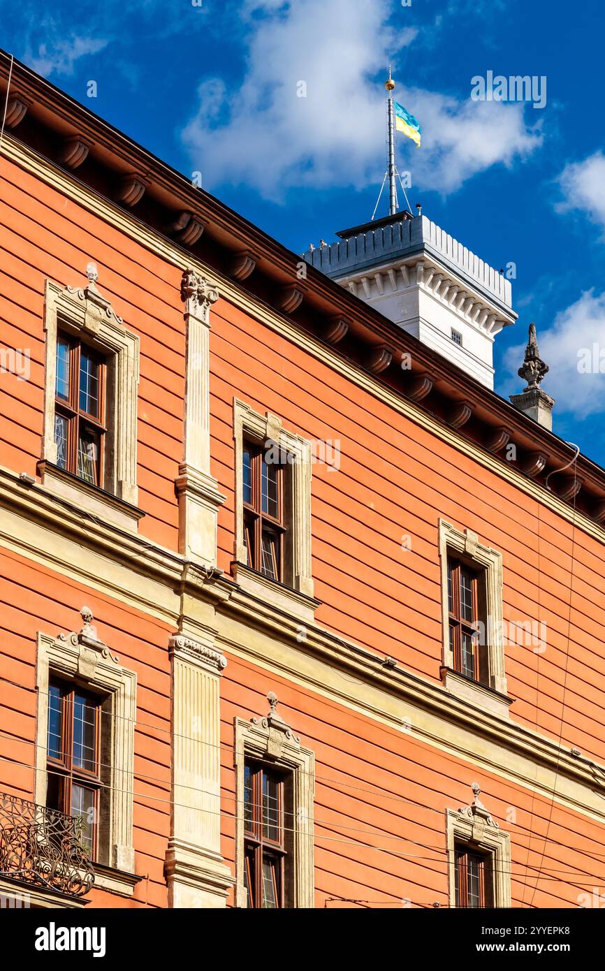 Das Gebäude hat viele Fenster und einen hohen Turm. Die Fenster sind rechteckig und das Gebäude ist orange Stockfoto